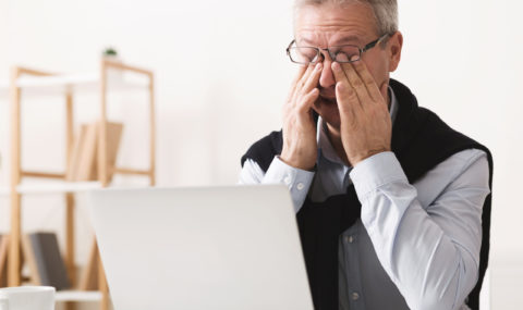 Hard day. Elderly man feeling tired, working on laptop