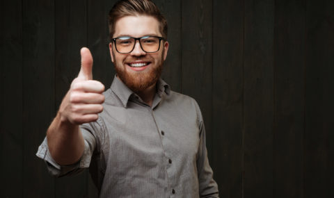 Portrait of a smiling man in glasses showing thumb up