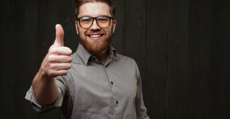 Portrait of a smiling man in glasses showing thumb up